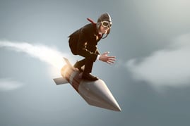 A business man representing iBuyers crouches on top of a fast rocket as they fly through a gray sky.