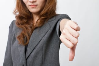 Business woman/real estate appraiser, dressed in gray suit puts her thumb down against iBuyers.
