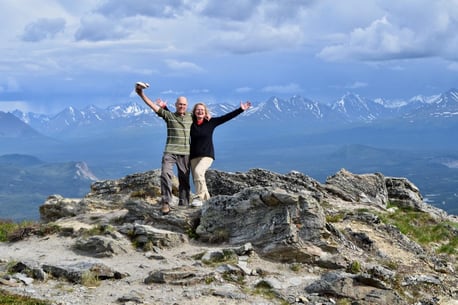 An odler couple standing on a mountain.